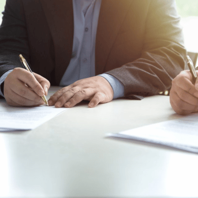 A closeup of a businessman's hands signing a document