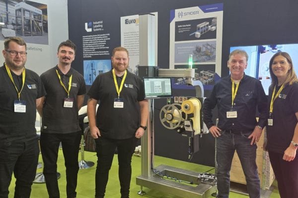 Five people stand in front of a stand at PPMA Show 2025. In the centre of the photo is an Evolabel machine