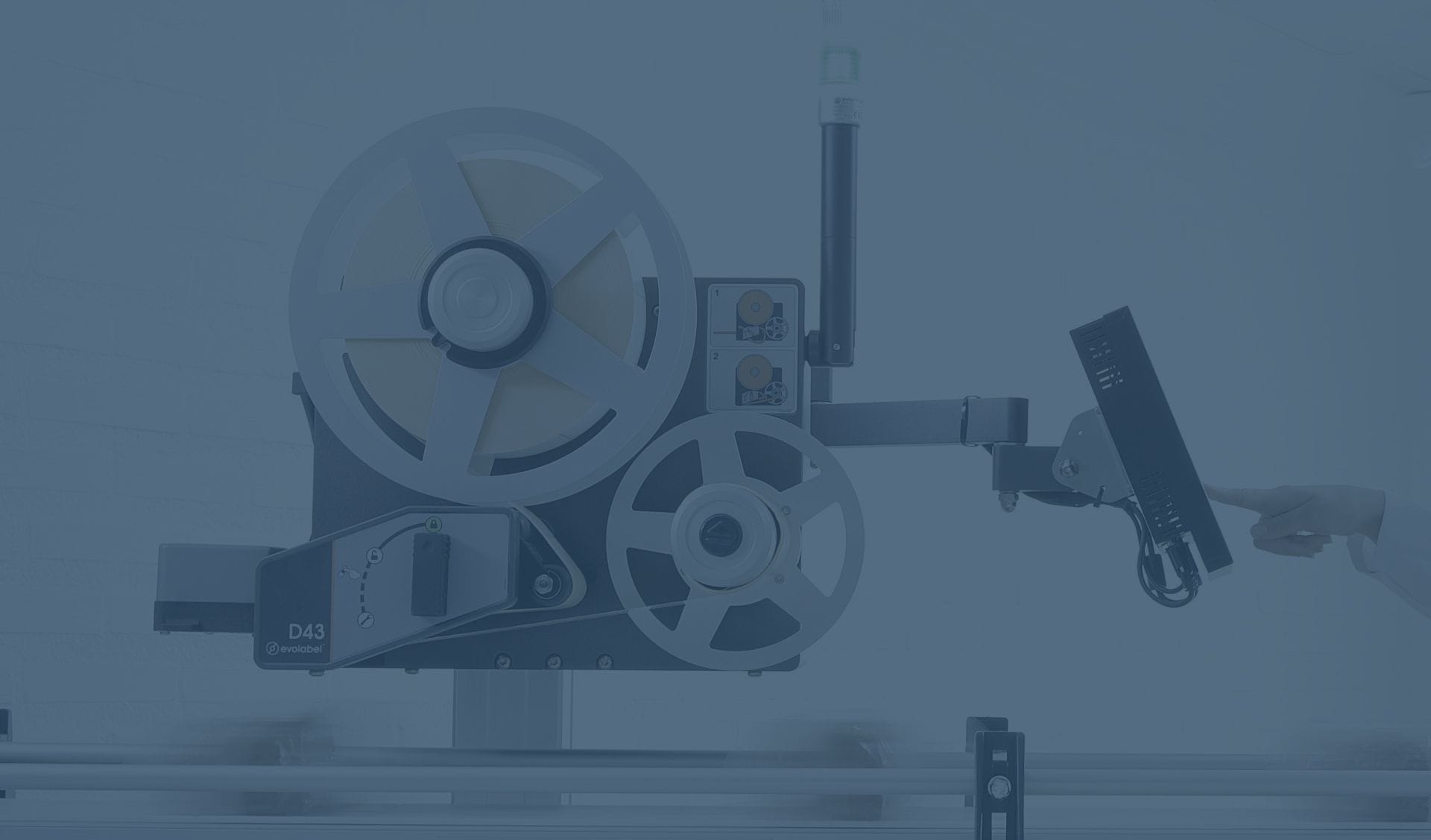 A hand presses a button on the digital screen of an Evolabel D43 label printer and applicator