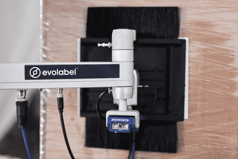 FlexWipe_Motorized-Stand-XL_LowRes_01-768x512 Applicator arm of an Evolabel FlexWipe machine applies a label to a pallet